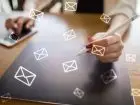 Jak napisać e-mail służbowy? - osoba pisząca na tablecie, w tle ikonki poczty