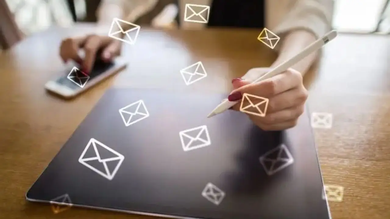 Jak napisać e-mail służbowy? - osoba pisząca na tablecie, w tle ikonki poczty