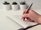 Promesa zatrudnienia - dłoń pisząca w notesie