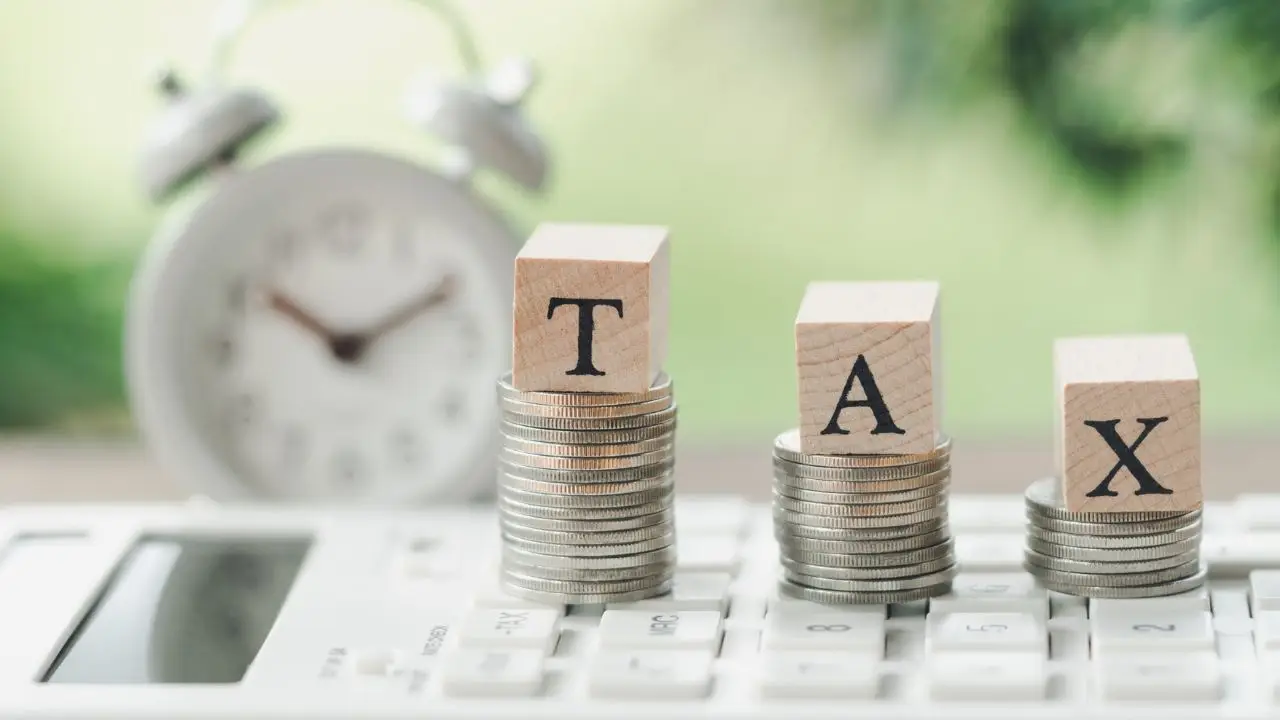 Skala podatkowa 2024 - napis tax na stosach monet, w tle zegar