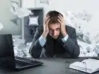 Trening Jacobsona - zestresowany pracownik przy biurku, wokół fruwające dokumenty