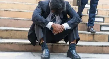 Smutny mężczyzna siedzący na schodach ze zwieszoną głową