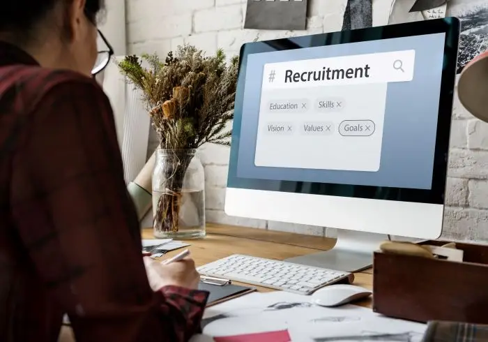 Assessment Center - osoba pracująca przy komputerze, na ekranie napis "recruitment"