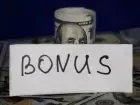 Premia dla pracownika - napis bonus na tle banknotów dolarów