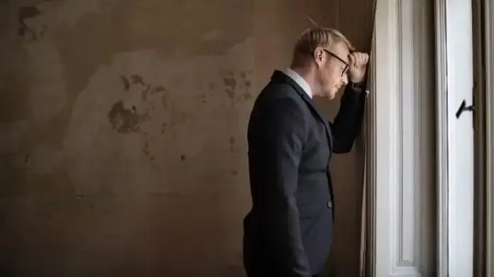 Skutki bezrobocia w Polsce - zasmucony mężczyzna oparty głową o ścianę