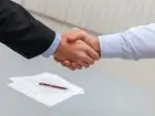 Umowa na czas nieokreślony - dwoje mężczyzn podających sobie dłonie, w tle dokumenty i długopis