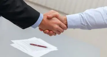 Umowa na czas nieokreślony - dwoje mężczyzn podających sobie dłonie, w tle dokumenty i długopis