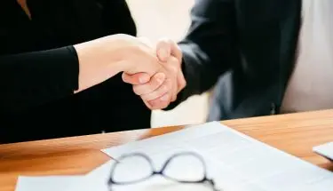 Umowa na czas próbny - osoby ściskające sobie dłonie nad umową