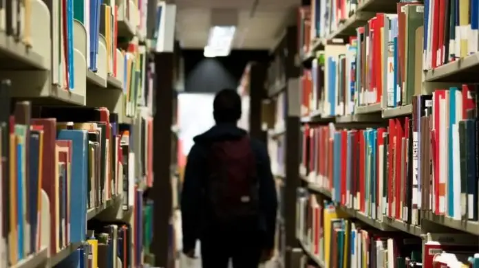 jaki kierunek studiów wybrać - student w bibliotece miedzy regałami