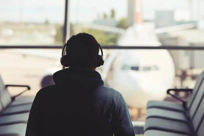 Mężczyzna z zakrytymi uszami na lotnisku, patrzący na samolot