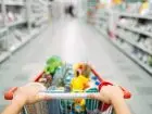 Kobieta pchająca wózek z zakupami w markecie