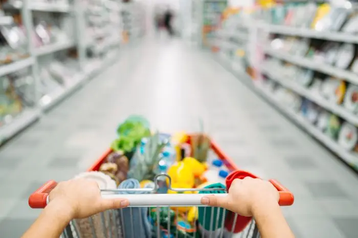 Kobieta pchająca wózek z zakupami w markecie