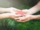 Figurka serca przekazywana na dłoniach przez jedną osobą, drugiej osobie