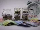Słoiki z monetami, podpisane "house, health, travel"