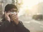 Mężczyzna zakrywający twarz maseczką, rozmawiający przez telefon