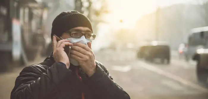 Mężczyzna zakrywający twarz maseczką, rozmawiający przez telefon