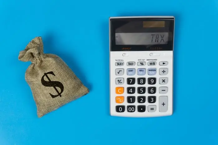 Klkulator i woreczek ze znakiem dolara na niebieskim tle