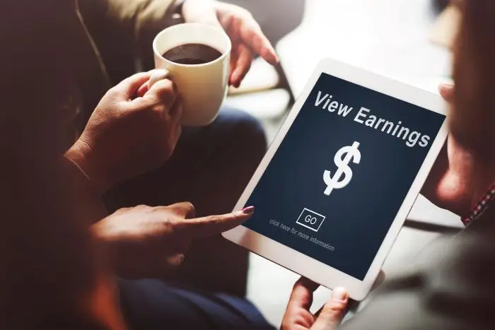 Pandemia a zarobki - dwie osoby przeglądające tablet z napisem "view earning"