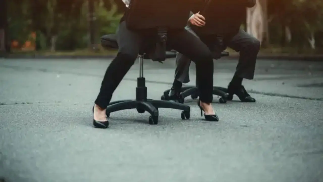 Pracownicy uciekający ulicą na krzesłach biurowych