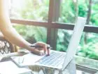 Zbliżenie na laptopa używanego przez kobietę z długopisem w dłoni