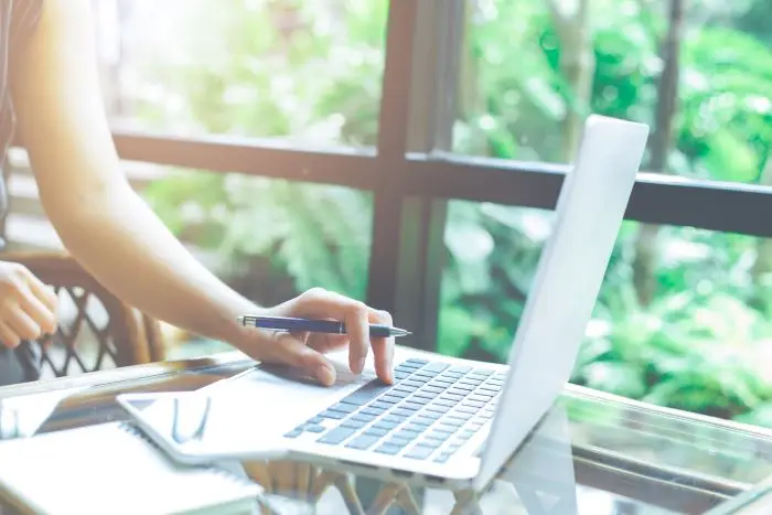 Zbliżenie na laptopa używanego przez kobietę z długopisem w dłoni