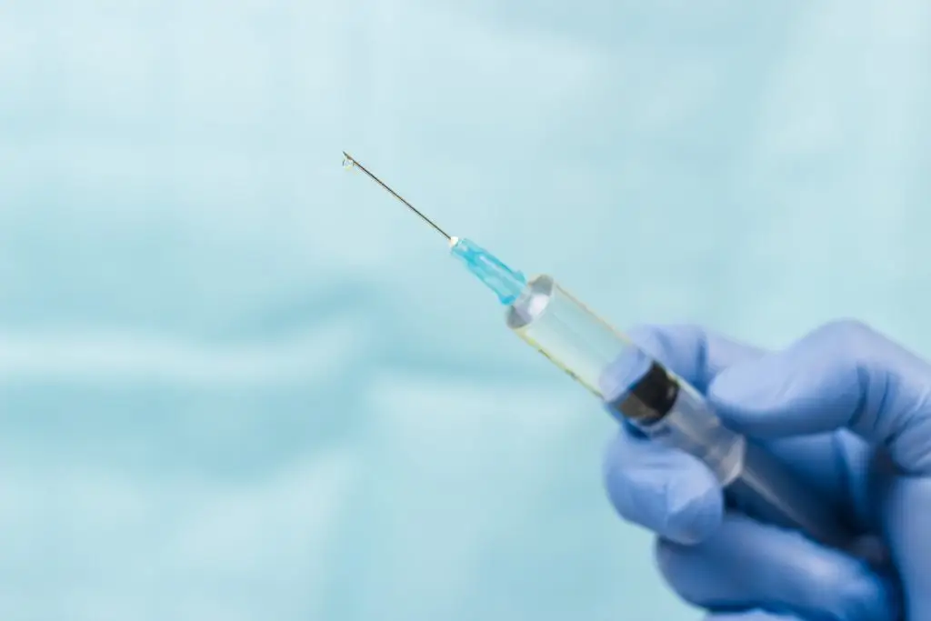 Kiedy wynaleziono szczepionkę na koronawirusa - strzykawka trzymana w dłoni w rękawiczce