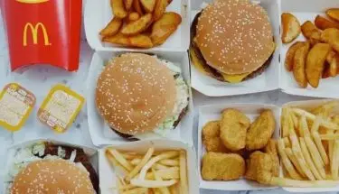 Zarobki w McDonald's - burgery, frytki i inne produkty McDonald's ustawione na stole