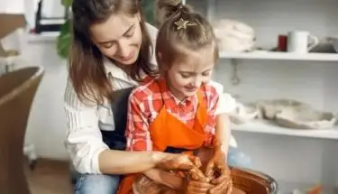 Kobieta z dzieckiem w trakcie wyrabiania gliny