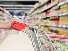 Kobieta w supermarkecie na zakupach, pchająca wózek zakupowy