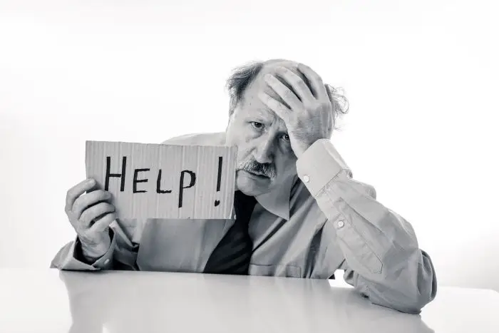 Mężczyzna trzymający kartkę z napisem help