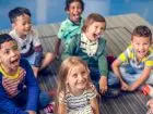 Jak założyć przedszkole - uśmiechnięte dzieci siedzące na podłodze