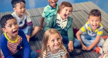 Jak założyć przedszkole - uśmiechnięte dzieci siedzące na podłodze