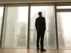 Mężczyzna stojący w oknie biurowca