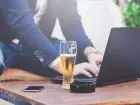 Mężczyzna pracujący przy laptopie, obok piwo