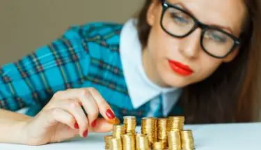Kobieta w okularach, licząca stosy monet