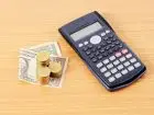 Kalkultor na blacie obok banknotów i monet