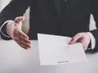 Mężczyzna wyciagający dłoń z umową w geście porozumienia