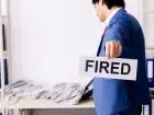 Mężczyzna w garniturze z kartką z napisem fired