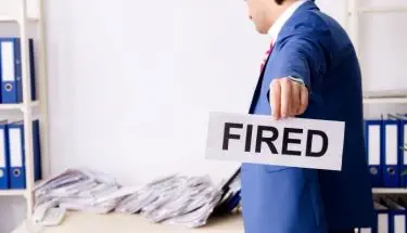 Mężczyzna w garniturze z kartką z napisem fired