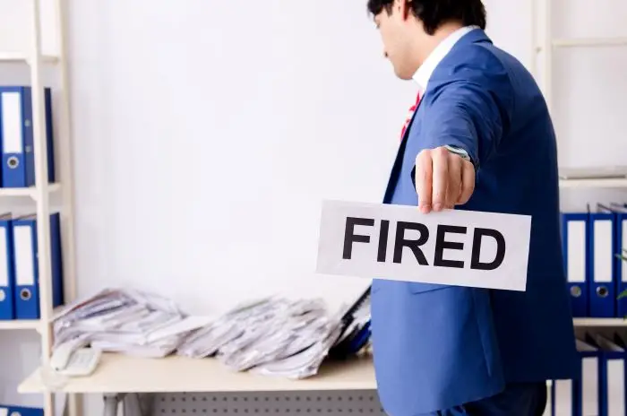 Mężczyzna w garniturze z kartką z napisem fired