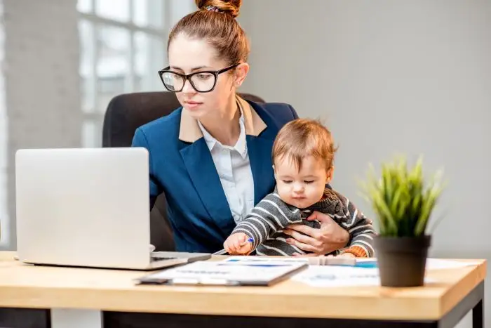 Mama w trakcie pracy przy laptopie, z dzieckiem na kolanach