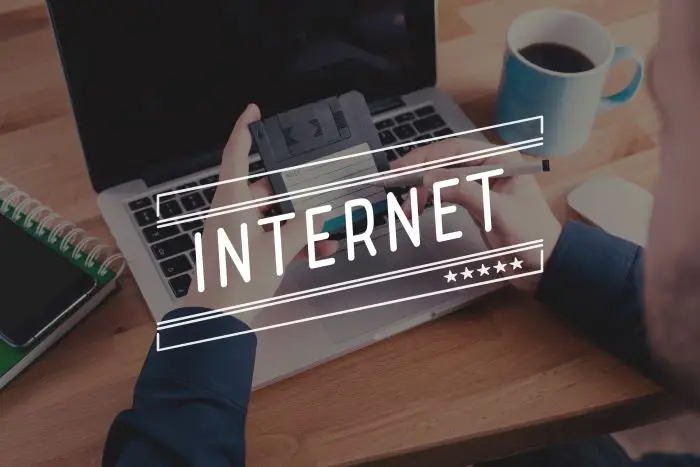 Napis internet na tle laptopa używanego przez mężczyznę