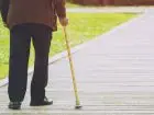 Emeryt idący o lasce
