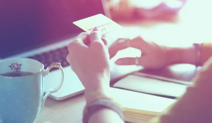 Osoba trzymająca kartę płatniczą na tle laptopa