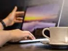 Otwarty laptop, obok kawa na biurku