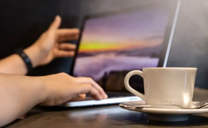 Otwarty laptop, obok kawa na biurku