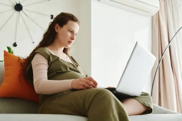 Kobieta wykonuje prace przy komputerze w ciąży