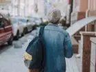 Emeryt z plecakiem idący chodnikiem