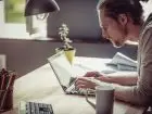 Koszty prowadzenia dzialalnosci w domu - męzczyzna w domu przy biurku pracuje na laptopie