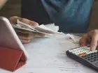Zbliżenie na mężczyznę przegladającego dokuemntację przy biurku, obok kalkulator